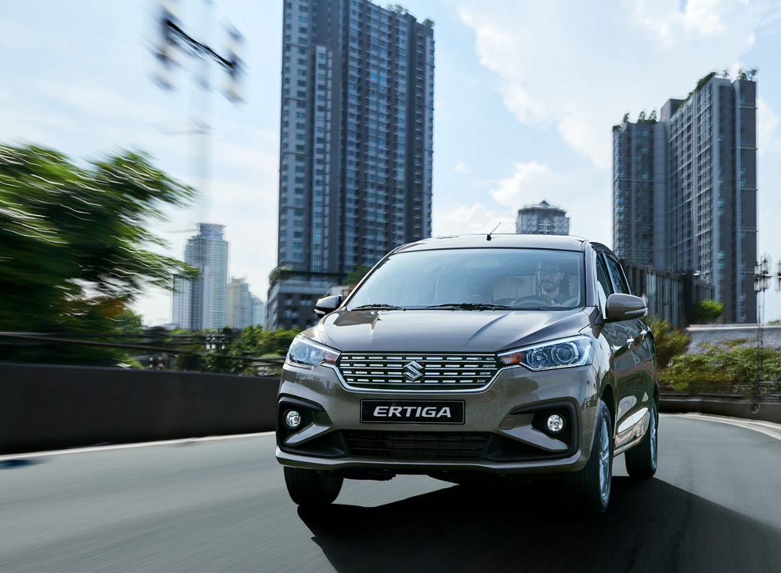 front view of suzuki ertiga driving on road with city buildings in background